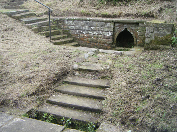 A recess in a stone wall with water